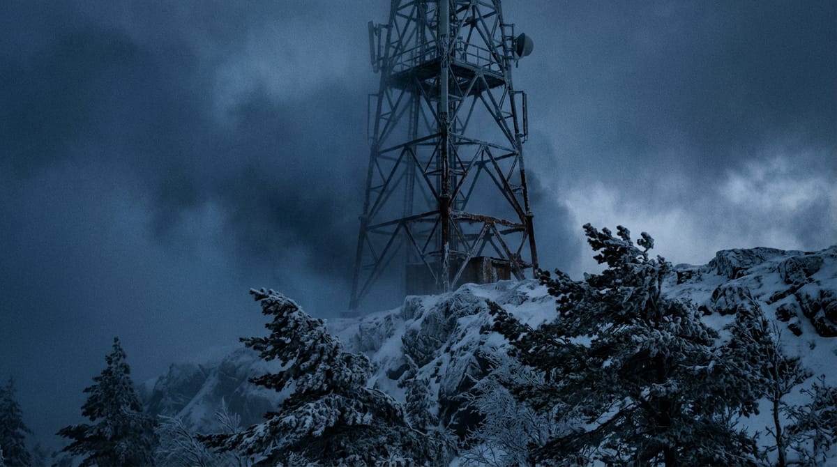 A solitary mobile telecommunication tower standing on a desolate, snowy hill. The tower is dark, no signal lights active, surrounded by a thick fog. In the background, fierce winds are bending the surrounding pine trees. High contrast photography, capturing the feeling of isolation and vulnerability.